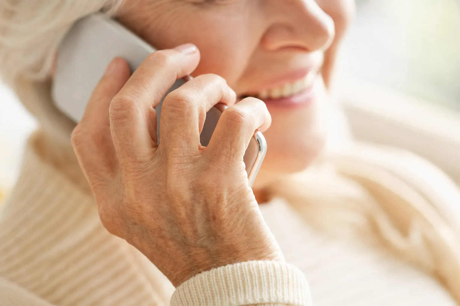 Close-up of older hands gently holding a phone during a call